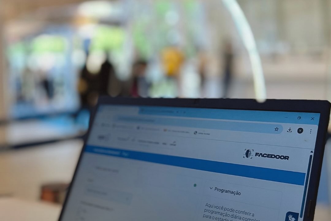 Plataforma da Facedoor aberta em um laptop durante o evento, com a marca do produto e a programação do dia