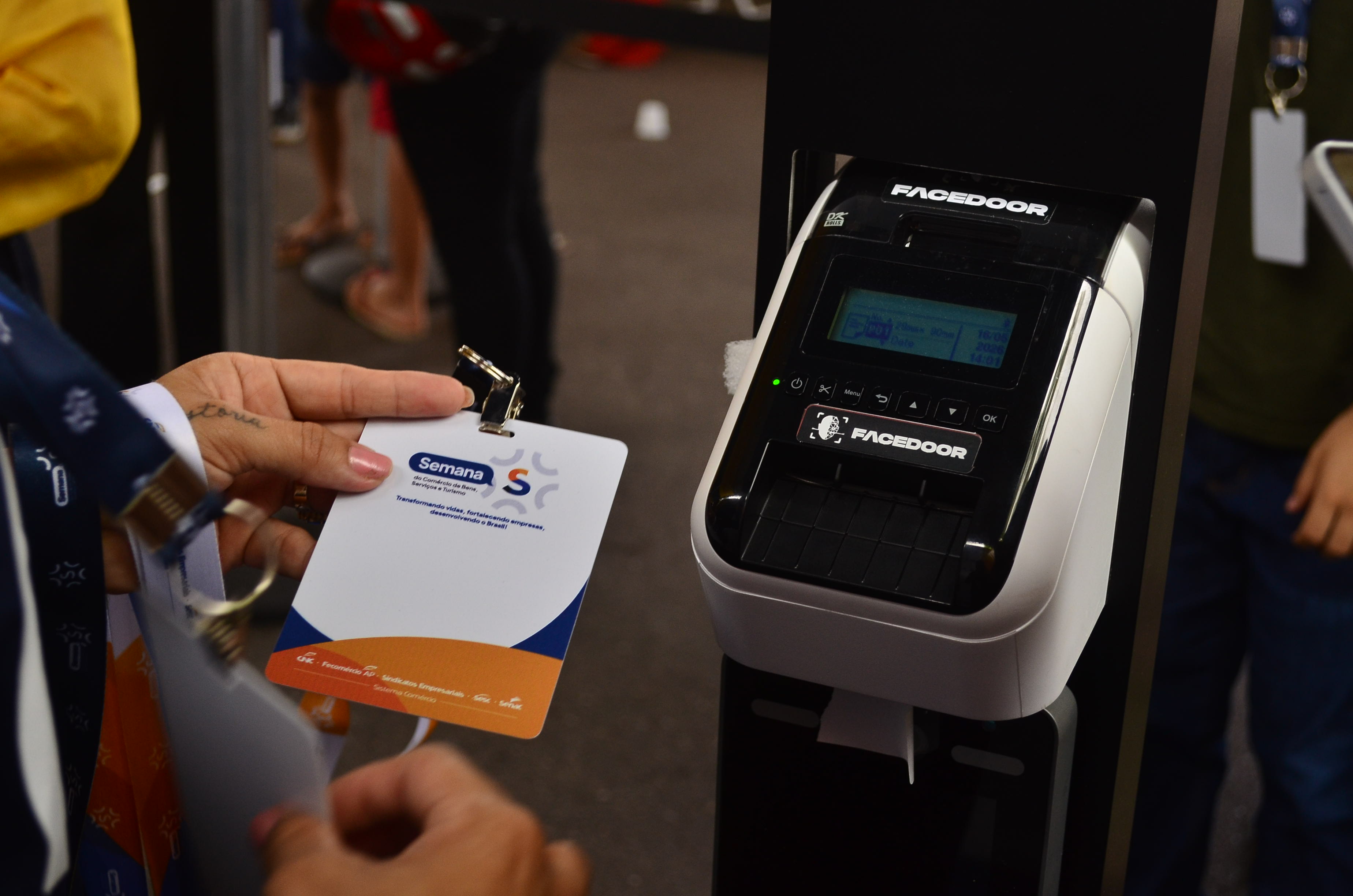 Credencial do evento recém-impressa ao lado da impressora com a marca Facedoor